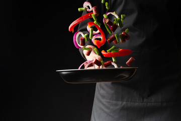 Chef preparing pepperoni sausages with green beans, sweet bell peppers and red onion rings, on a...