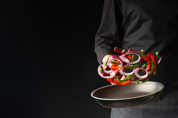 Chef preparing pepperoni sausages with green beans, sweet bell peppers and red onion rings, on a black background, a recipe book, German sausages, freeze in motion