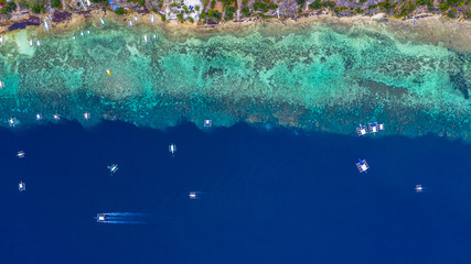 Aerial view of Filipino boats floating on top of clear blue waters, Moalboal is a deep clean blue ocean and has many local Filipino boats in the sea. Moalboal, Cebu, Philippines.