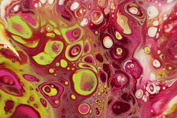 Close-up on an abstract acrylic pour painting on canvas in shades of magenta, light green, yellow, and white.