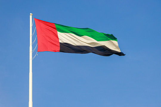 Flag of United Arab Emirates flying in the wind against a blue sky