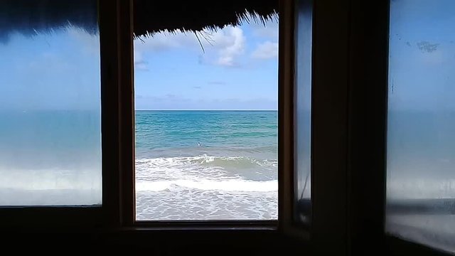 Sea view at window with unrecognizable surfer