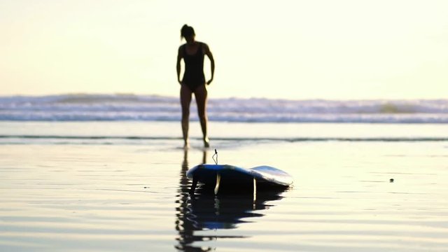 beautiful young surfer girl walking on the beach to paddle sup surfboard. slow motion. Concept of harmony with nature, healthy living