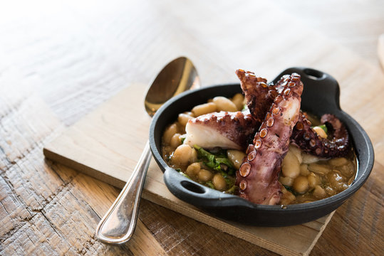 Grilled octopus with beans in a skillet