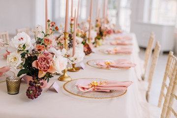 Wedding decoration table in the hall, floral arrangement. In the style vintage. Decorated dining table with flowers for guests and newlyweds, in peach-pink & pastel color. Beautiful table setting.
