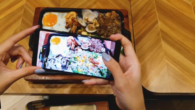 Woman hands taking photo of her lunch with smart phone in the restaurant. Shot in 4k resolution