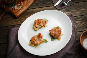 Chicken medallions on a pillow of vegetables. Cafe menu on a wooden background in warm colors with copy space.