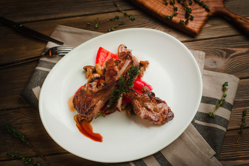 Grilled ribs with mushrooms, sweet peppers and thyme. Cafe menu on a wooden background in warm colors with copy space.