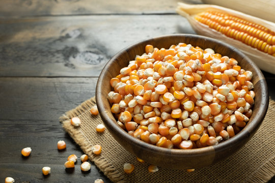 Dry corn seeds in the wooden bowl put on table.