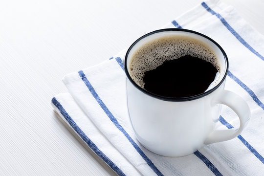 A white cup of black coffee put on table with napery. Morning healthy coffee concept.