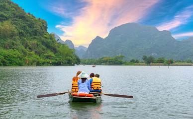 Ninh Binh, Vietnam - April 5th, 2019: People rowing boats for carrying tourists on Ngo Dong river of the Tam Coc National Park. Tam Coc is a popular tourist destination in Ninh Binh, Vietnam.