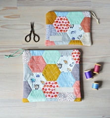 Colorful hexagon quilted pouches, retro scissors and thread on the wooden table