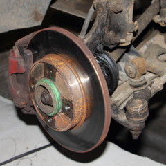 Brake disk and destroyed CV joint duster, hub and sterering rod - repair car suspension and gear drive on left side with removed wheel