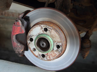 Car brake system - used unvented brake disk with red brake caliper with brake pads