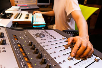 asian male professional producer mixing audio tracks on digital sound mixer in home studio. music production concept