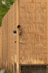 surveillance camera and speaker on an old yellow metal fence