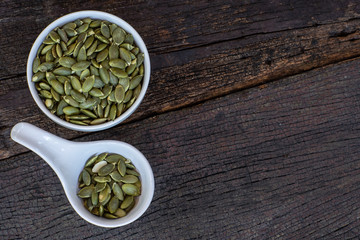Pumpkin grain in wooden bowl and fresh pumpkin fruit on classic wooden table background, cereal