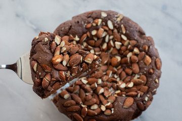 Piece of stack homemade dark chocolate brownies with salted almonds on a table