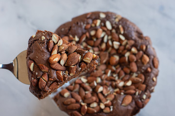 Piece of stack homemade dark chocolate brownies with salted almonds on a table