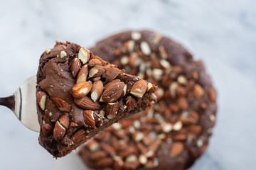 Piece of stack homemade dark chocolate brownies with salted almonds on a table