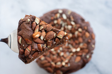 Piece of stack homemade dark chocolate brownies with salted almonds on a table