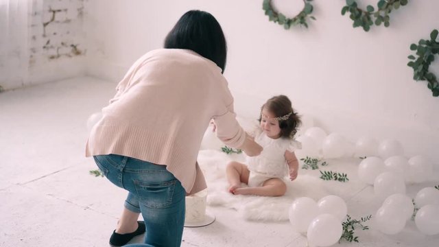 Female photographer takes pictures of little baby in photo studio.