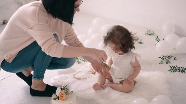 Woman photographer is combing baby girl before taking pictures of her in photo studio.