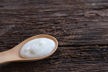Natural homemade plain organic yogurt in wood spoon on wood texture background