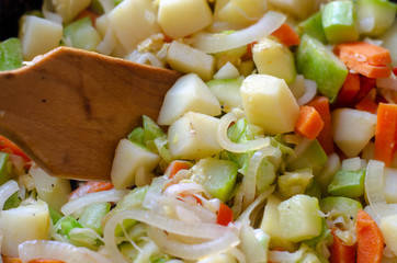 simple vegetable stew with potato, carrot, zucchini and onion on the old frying pan