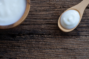 Natural homemade plain organic yogurt in wooden bowl and wood spoon on wood texture background