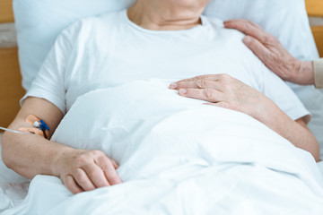 Fototapeta na wymiar partial view of sick senior woman with husband in hospital