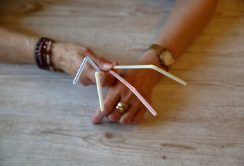Senior woman hands with four plastic drinking straws close up