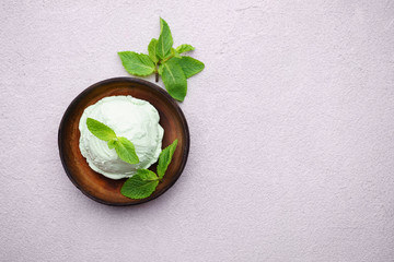 Mint ice cream scoop and peppermint leaves on stone table, copy space. Food background, summer refreshing concept, traditional seasonal cold sweets