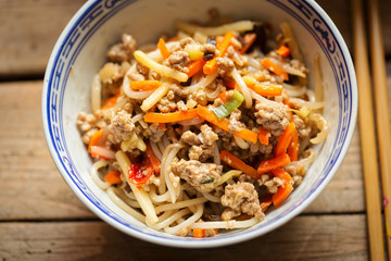 Chinese pork noodle stir fry with egg noodles and vegetables in bowl 