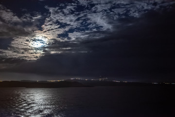 Fototapeta na wymiar Moon partially hidden by clouds over the island of Salamina