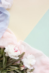 Flowers composition made of pink flowers and pastel scarf. Flat lay, top view, copy space. Pastel woman background