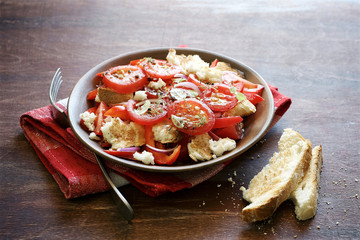 Tomatoes and bread salad. Traditional Italian salad Panzanella. Brown wood background
