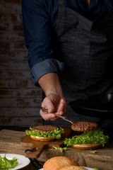 Home cooking burgers and french fries with your hands on a dark wooden background. -