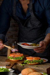 Home cooking burgers and french fries with your hands on a dark wooden background. -