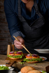 Home cooking burgers and french fries with your hands on a dark wooden background. -