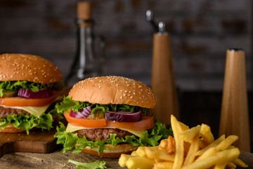 Home cooking burgers and french fries with your hands on a dark wooden background.