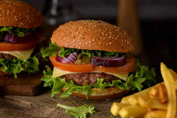 Home cooking burgers and french fries with your hands on a dark wooden background.