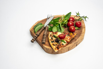 on a white background isolated piece of pizza, on a wooden board, next to fresh basil leaves and tomatoes