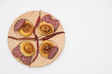 Salted dough. sliced sausage and chili peppers on a wooden board