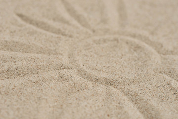 Fototapeta na wymiar sun drawing on sand background selective focus