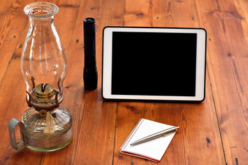 Writing equipments placed next to gadget plus a classic vintage lantern