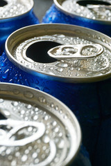 Close up of blue soda cans with open pull tab and condensation or water drops