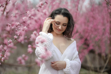 Lady in blooming bushes. woman in white sweater and skirt.