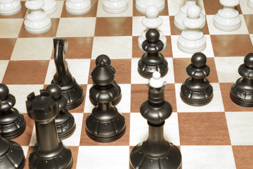 Wooden chessboard under black pawns like a strategy theme