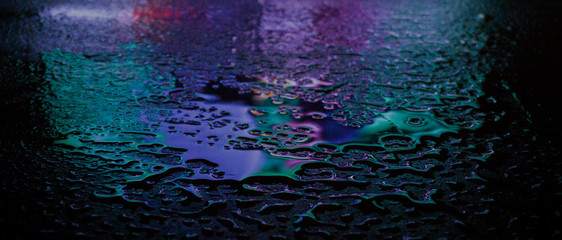 Wet asphalt, night scene of an empty street with a little reflection in the water, the night after the rain. Abstract dark neon background with a wet surface, reflection, neon, glare, blurred bokeh.
